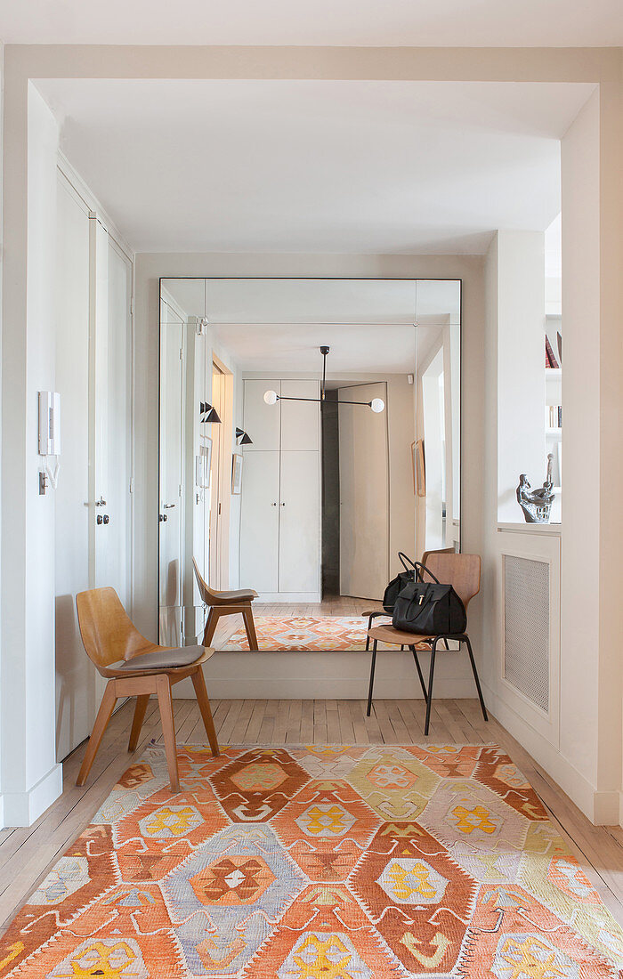 Large mirror on wall in hallway with kilim rug in shades of orange