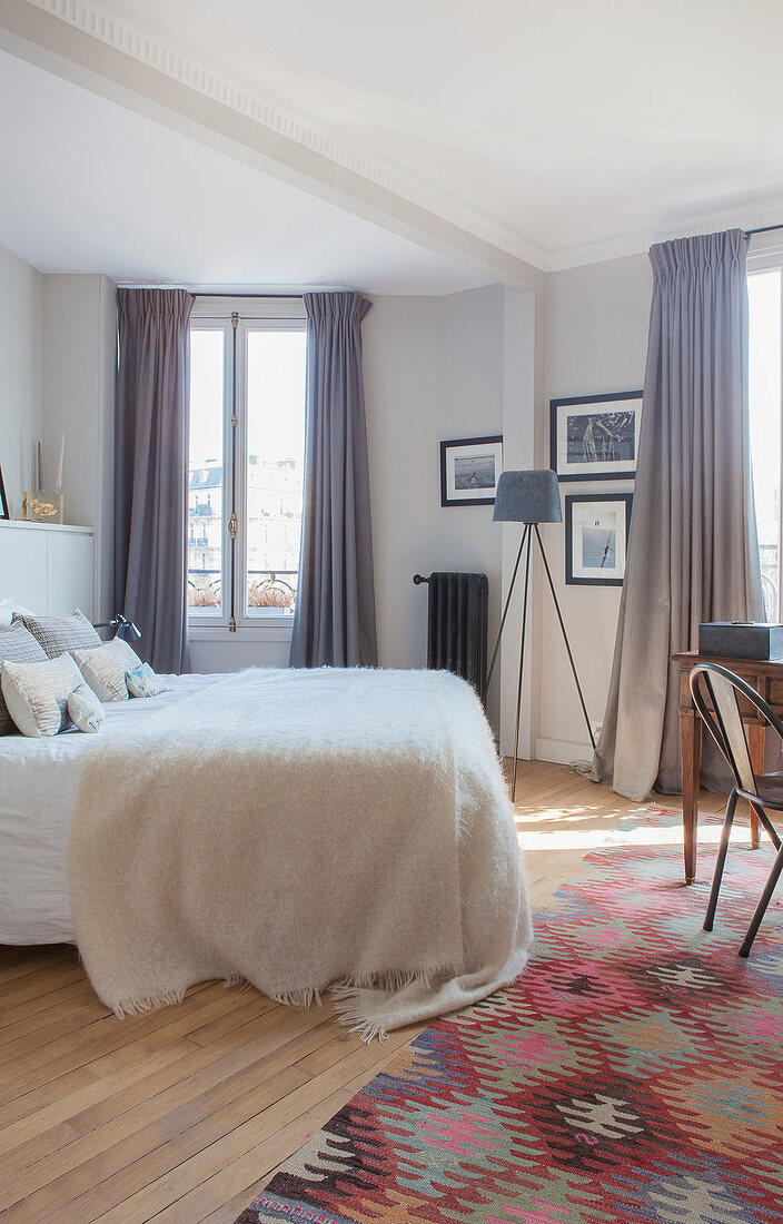 Brightly patterned rug next to bed in polygonal room