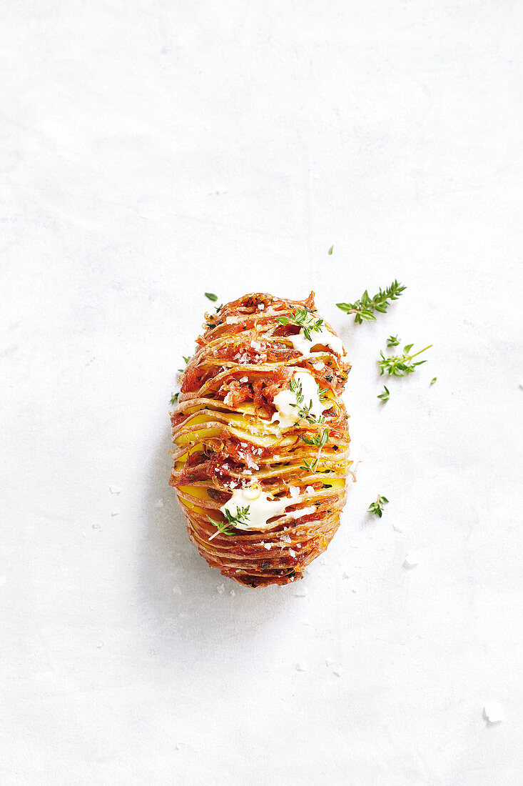 A hasselback potato with caramelized onions and thyme