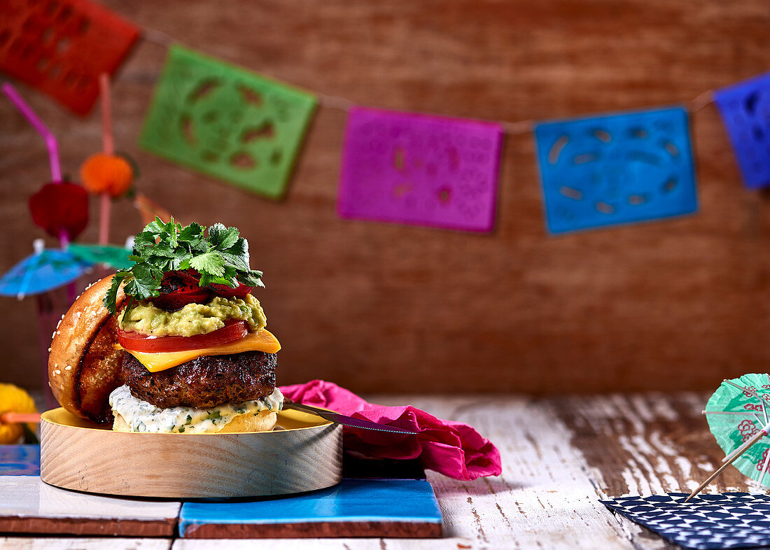 A cheeseburger with lime mayonnaise, guacamole, tomatoes and peppers