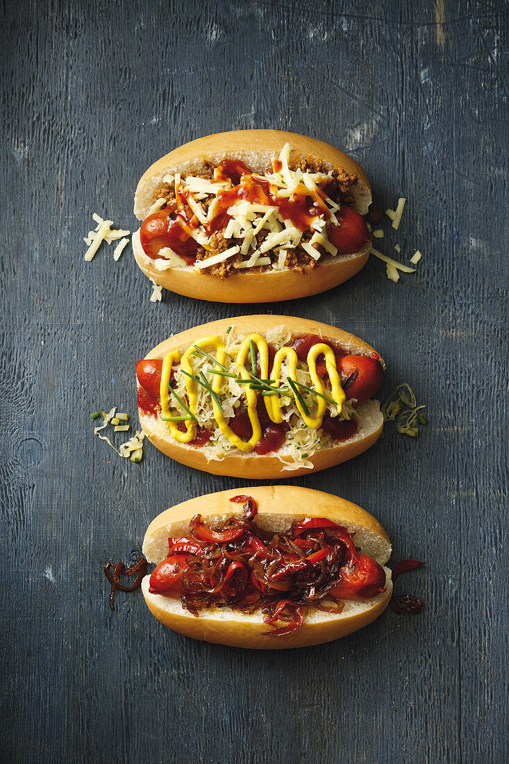 Verschiedene Hot Dogs: würziges Chili Dog, Hot Dog mit Sauerkraut, Gurke und Senf, Hot Dogs mit süsser Zwiebel und Paprikarelish