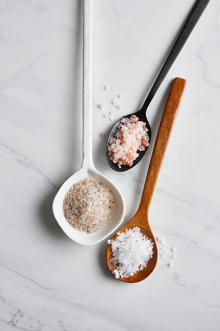 Sea salt, rock salt and Himalayan salt on spoons