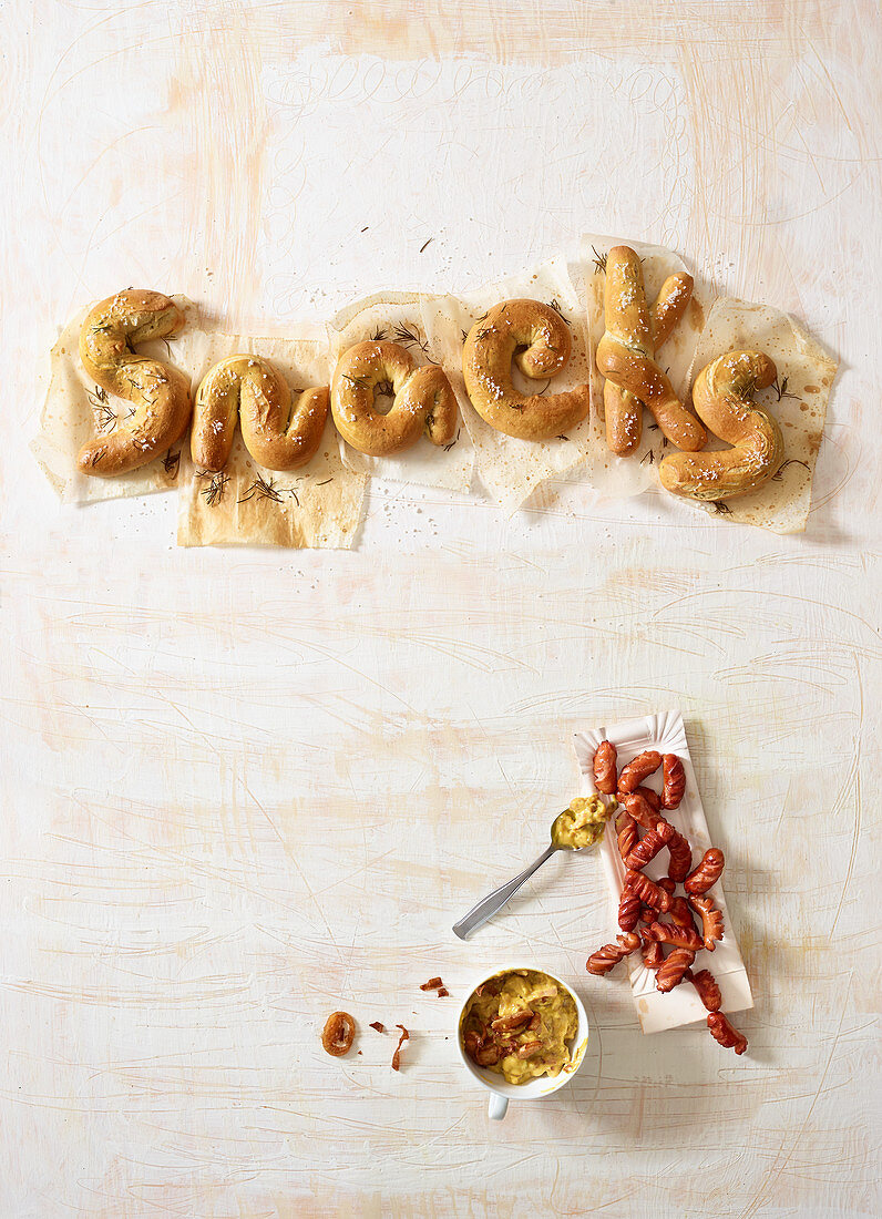 Schriftzug Snacks aus Salzgebäck und Miniwürstchen mit Senf