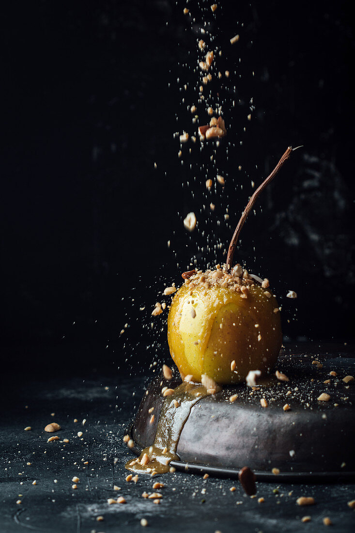 Karamellapfel mit gehackten Nüssen bestreuen