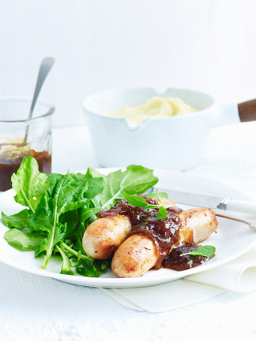 Chicken sausages with sage and onion sauce served with rocket salad
