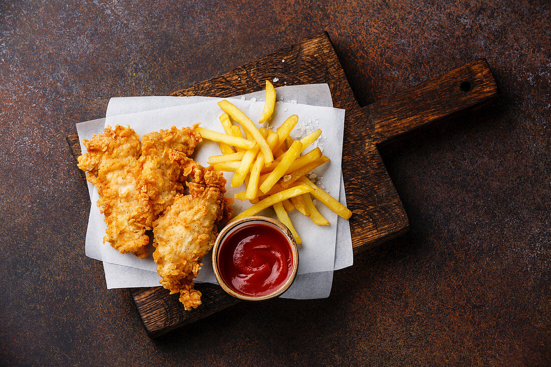 Fish and Chips mit Ketchup (Fastfood, England) auf dunklem Untergrund