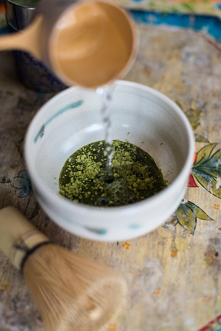 Hot water being poured over matcha powder