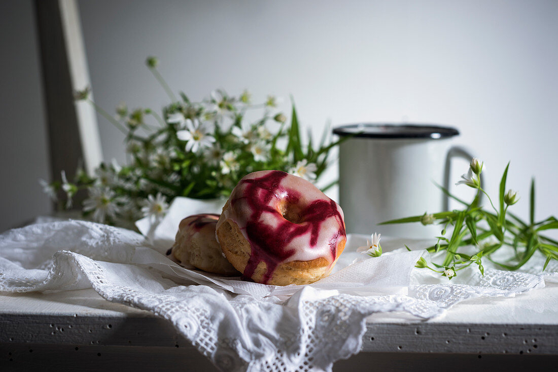 Vegan doughnuts with two types of glaze on an old wooden chair with coffee and flowers