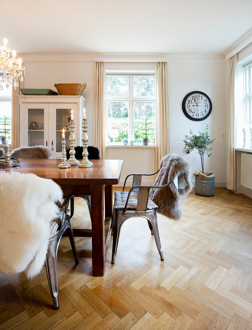 Metallstühle mit Schaffellen am Holztisch im Esszimmer