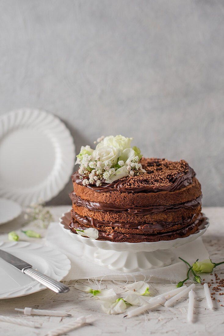 Chocolate cake on a white cake stand with flowers
