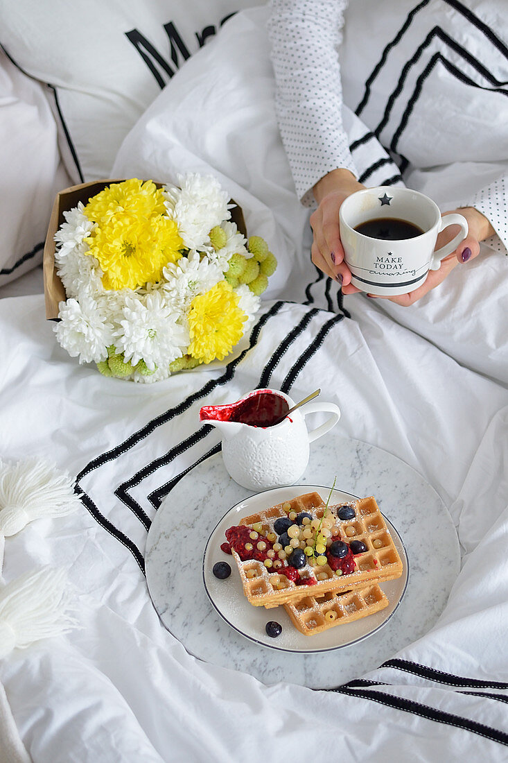 Frühstück im Bett mit Kaffee und Waffeln mit frischen Beeren