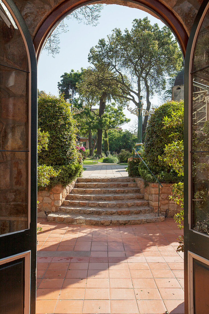 Blick durch Bogentür über Terrasse und Treppe in den Garten