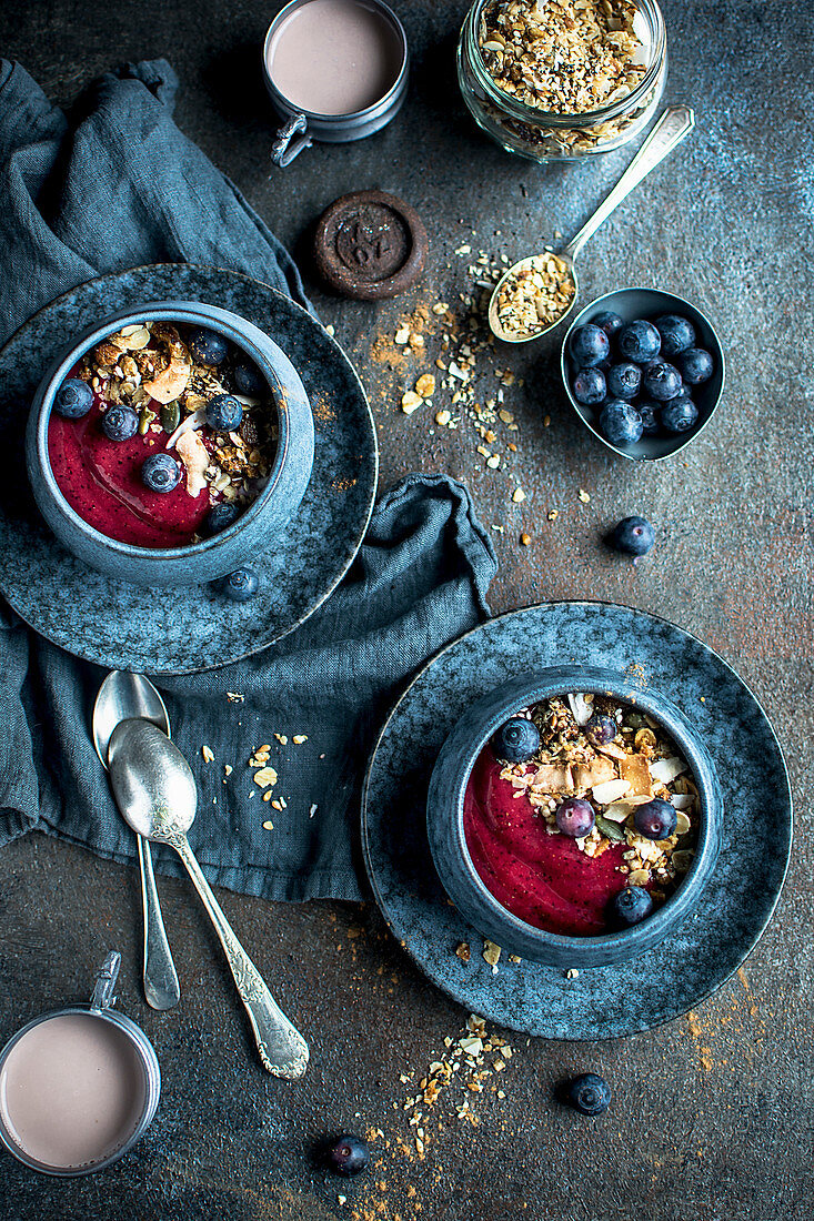 Breakfast bowls with blueberries, cereals, fruit mousse and drinking chocolate