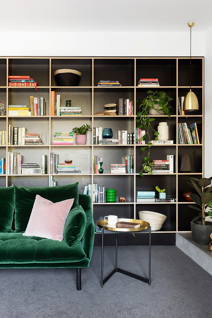 Dark green velvet sofa against a black shelf