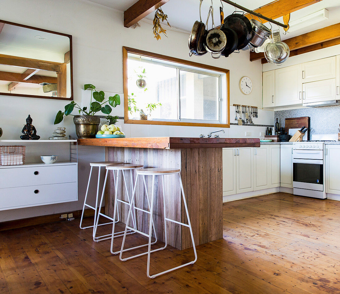 Wooden breakfast bar with filigree bar stools in an open kitchen