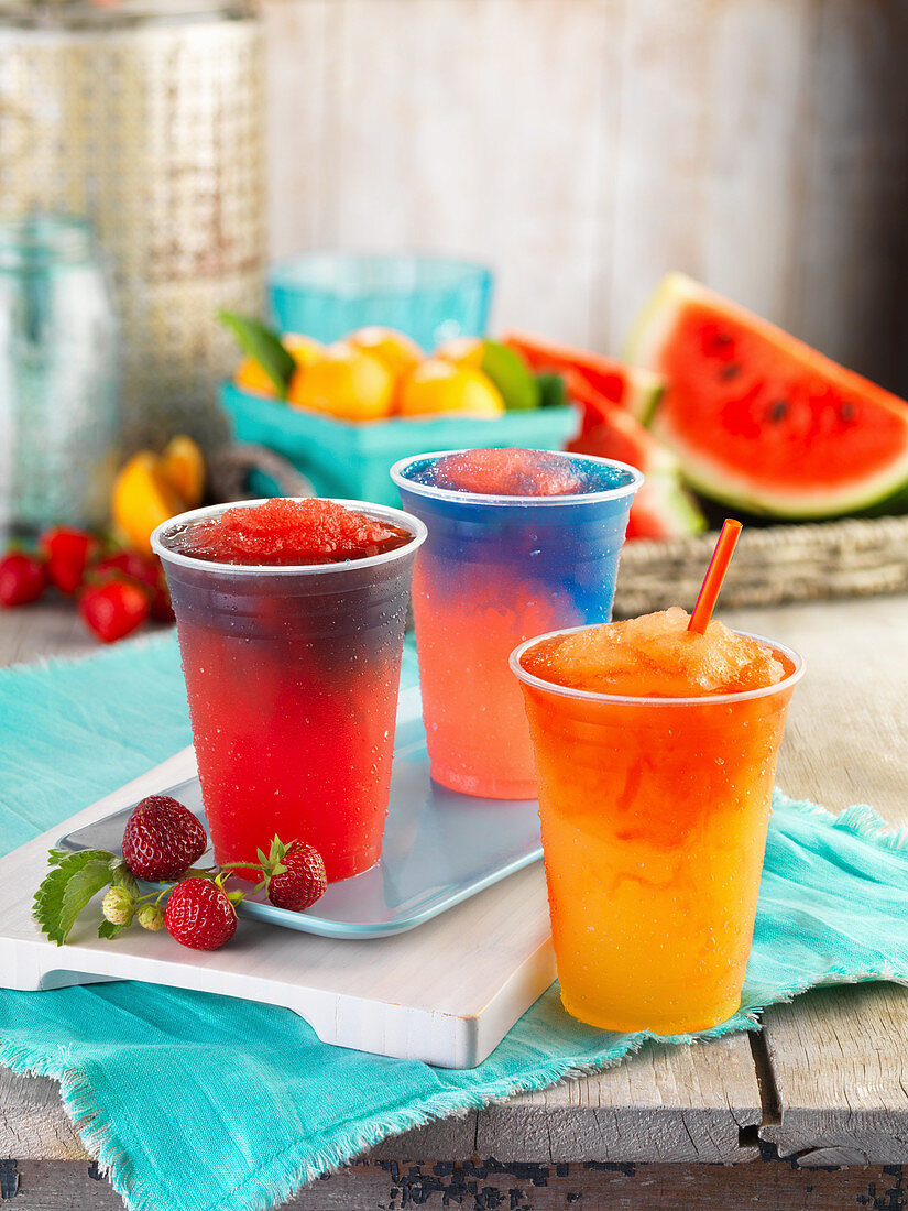 Three different fruity slushies in plastic cups