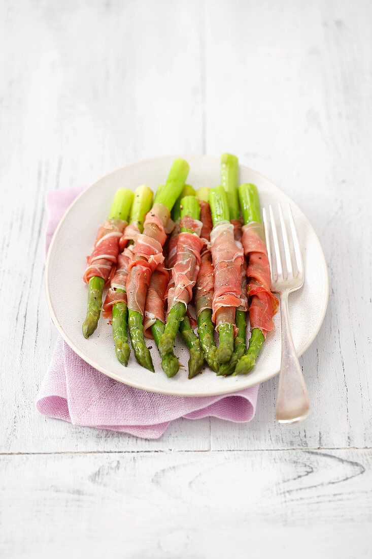 Cooked asparagus wrapped in prosciutto
