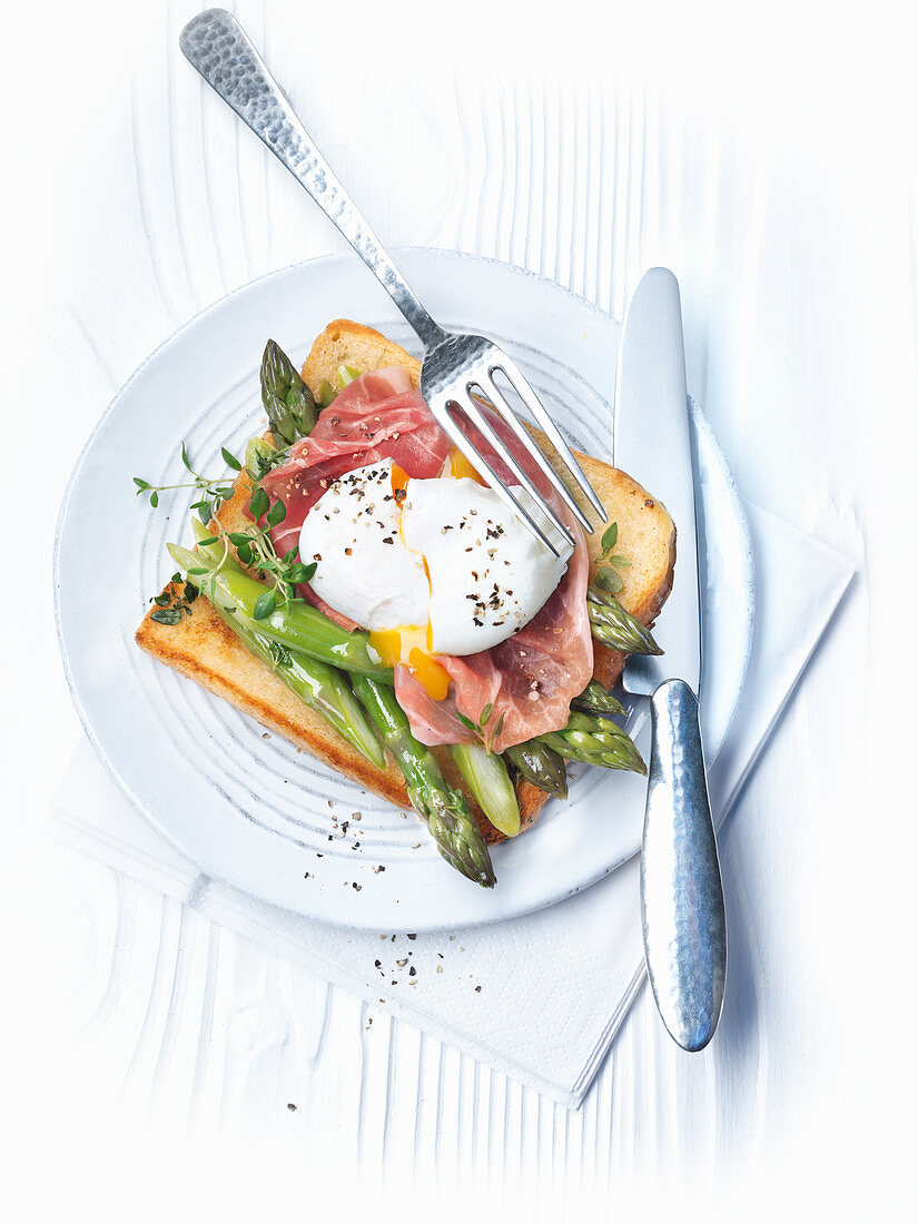 A poached egg on post with Parma ham and green asparagus