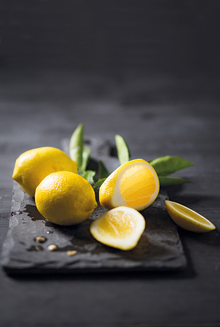 Lemons, whole and sliced, on a chopping board