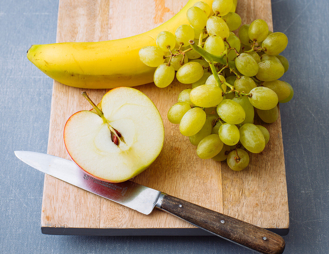 Half an apple, banana and grapes