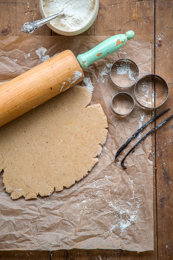 Vegan biscuit dough on baking paper with a rolling pin