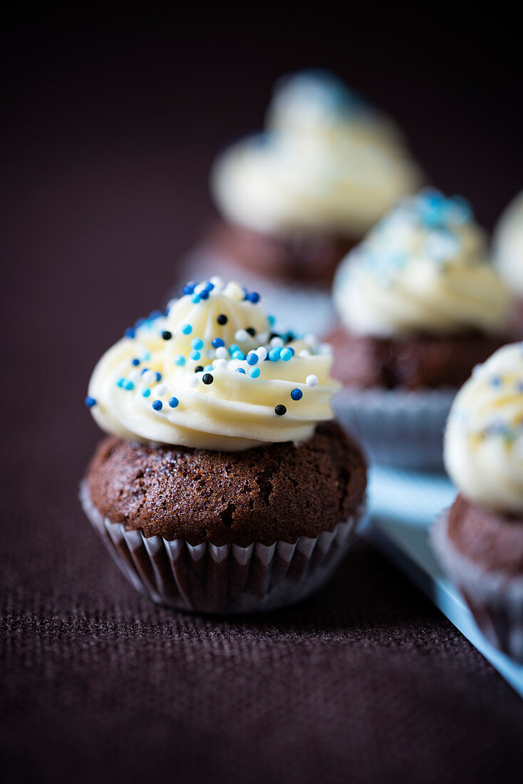 Mini chocolate vegan cupcakes with tonka bean cream and sugar sprinkles