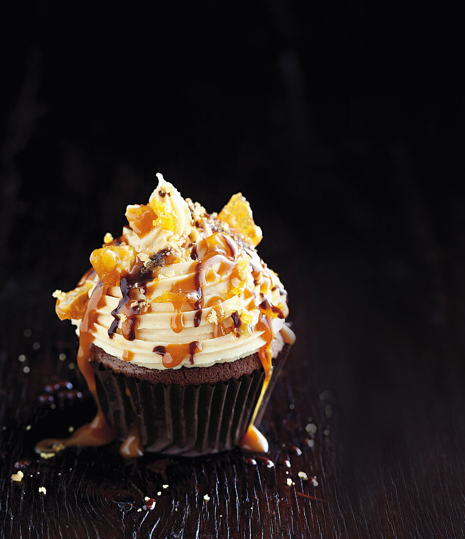 A chocolate cupcake with peanut butter and caramel sauce