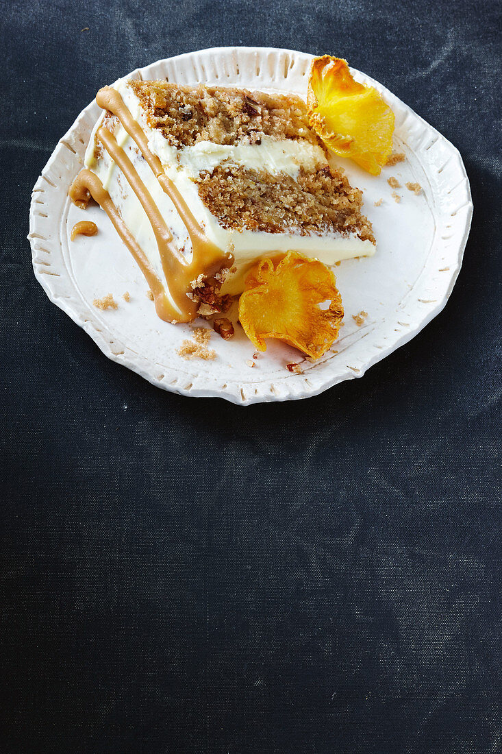 Stück Hummingbird Cake mit Ananas, Bananen, Kokosraspeln, Pecannüssen, Karamelsauce, Frischkäse, Zimt und Whisky