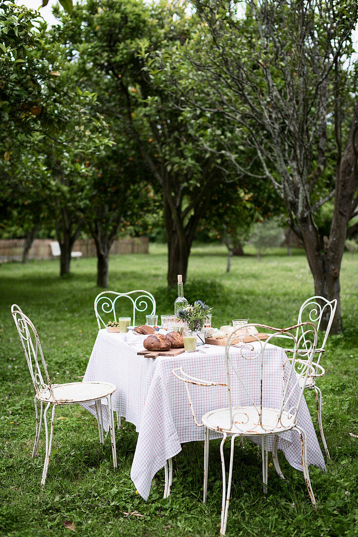 Romantisch gedeckter Tisch mit Metallstühlen in sommerlichem Garten