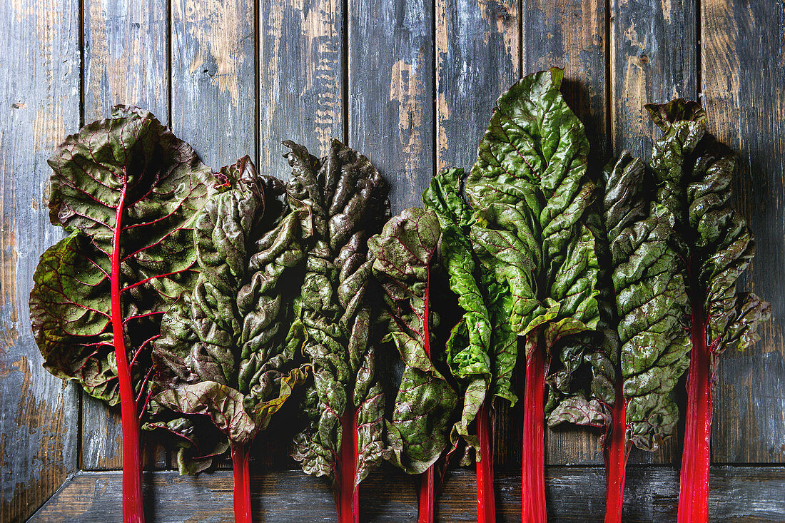 Leaves of fresh organic purple chard mangold over old wooden plank background
