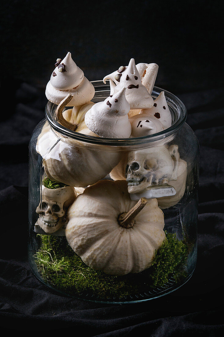 weiße Baisergeister für Halloween dekoriert mit Grusel-Schädeln und Kürbissen im Glas