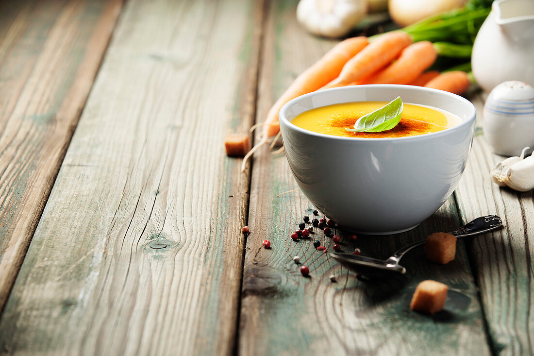 Vegetable cream soup in bowl over old wooden background