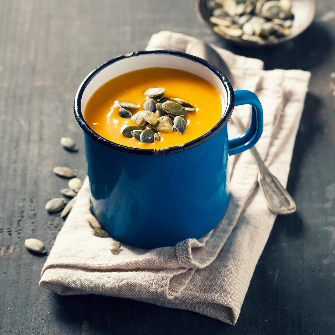 Pumpkin soup in a metal pot on a wooden surface