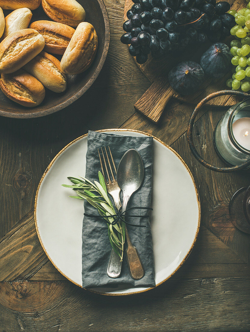 Holiday table party decoration setting, fresh fruits, bread buns, olive tree branch over wooden background