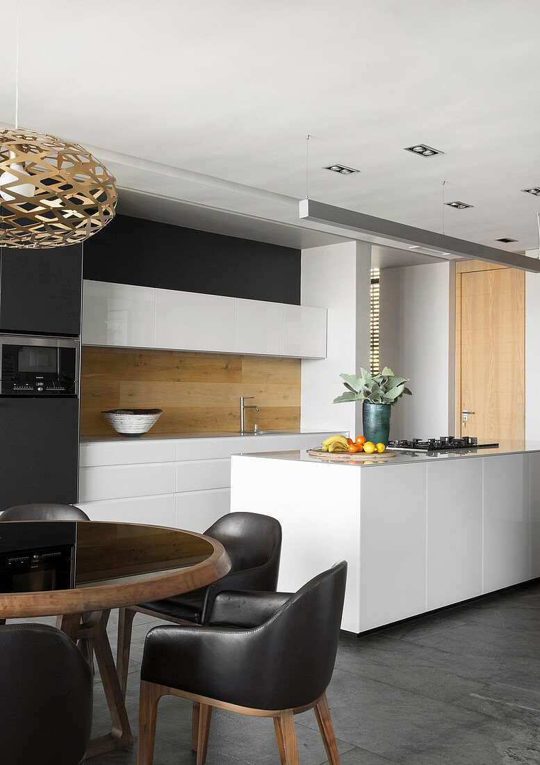 Black upholstered chairs at round table in front of open-plan kitchen