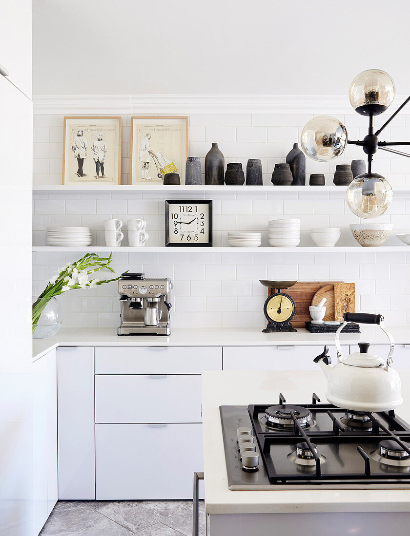 Shelves and gas hob on island counter in white kitchen