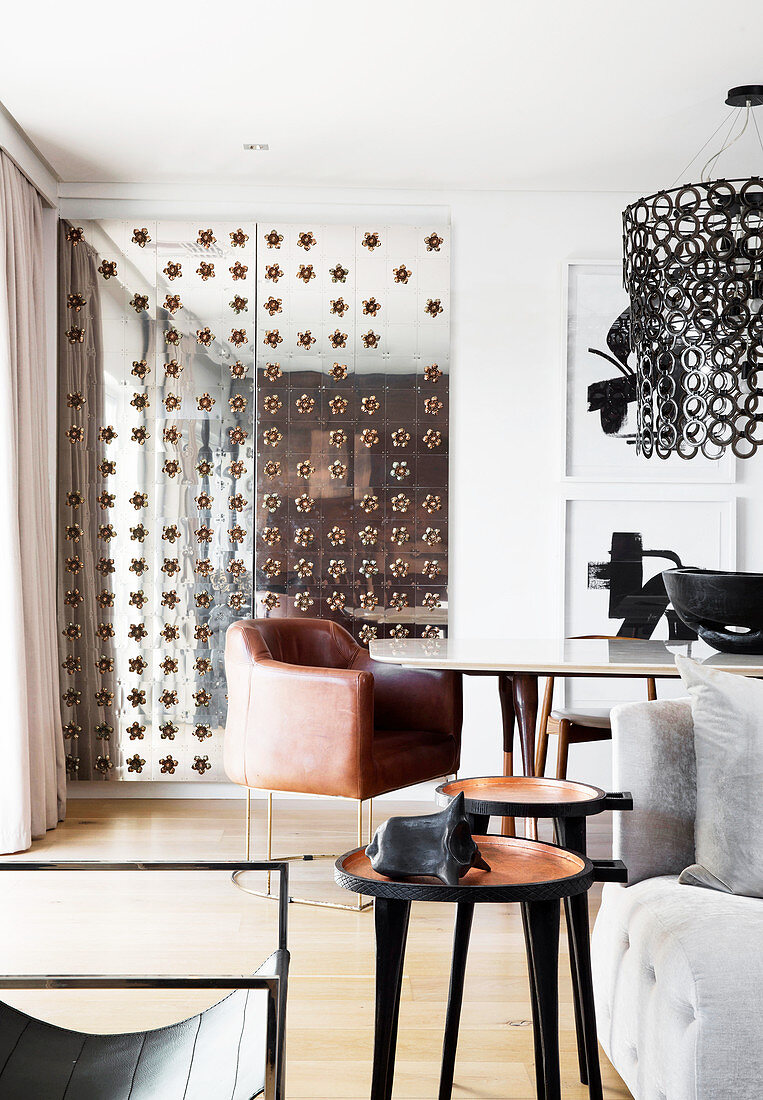 View past side table into dining area with designer leather armchair and mirrored door