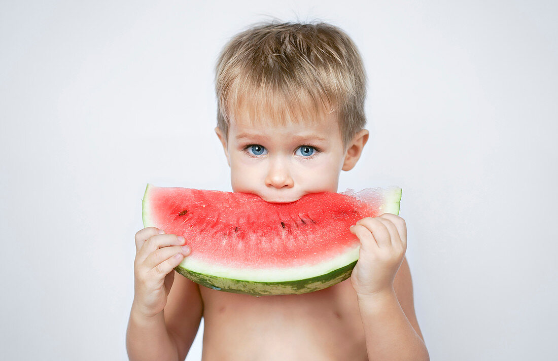 Kleiner blonder Junge beisst in Melonenspalte