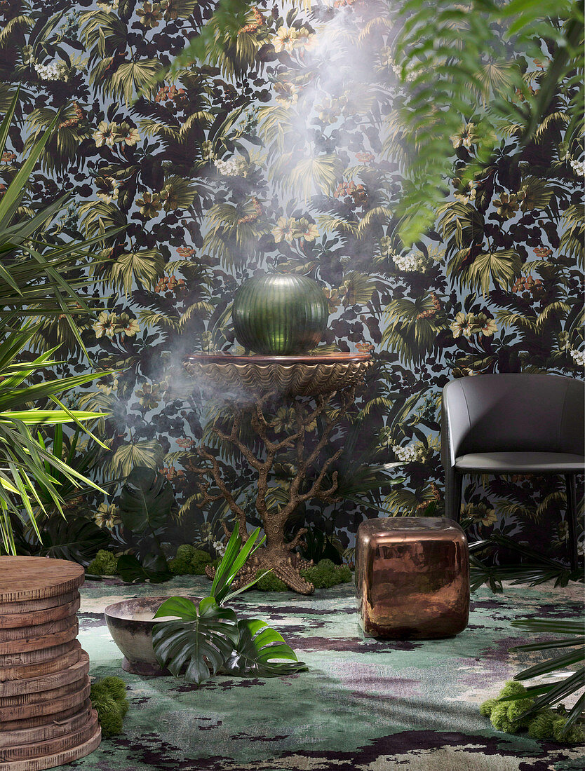 Round side table, armchair and cube table against wallpaper with plant pattern