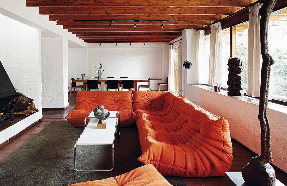 Orangefarbenes Designersofa im Wohnzimmer mit Balkendecke