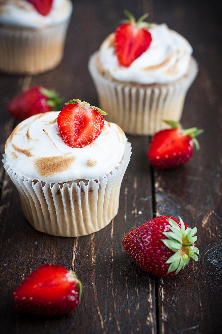 Erdbeer-Baiser-Cupcakes auf Holzuntergrund