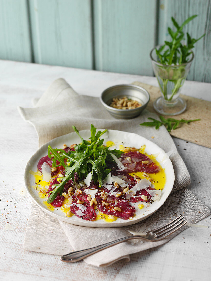 Straussen-Carpaccio mit Rucola, Pinienkernen und Parmesan