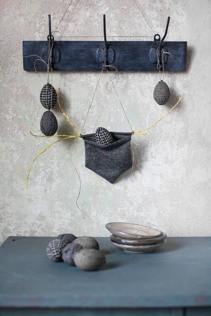 Easter eggs wrapped in fabric hung from hooks and on table