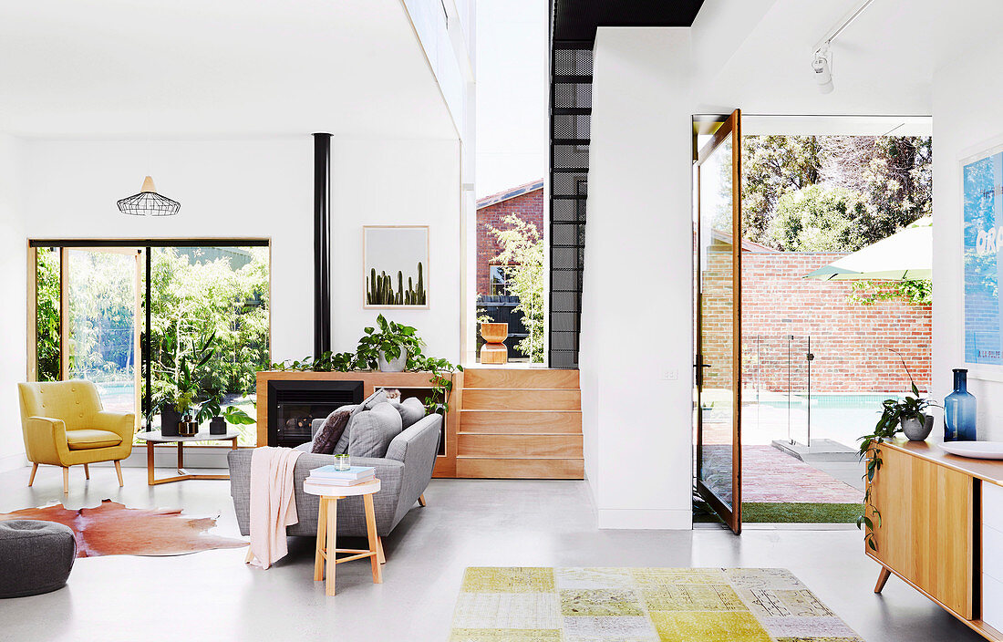 Bright, open living room in retro style with stairs and terrace access