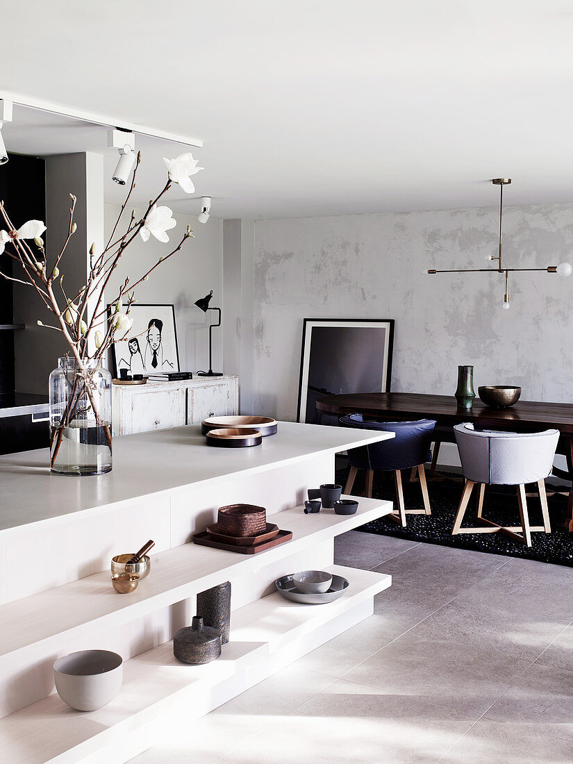 Kitchen island with open shelves and magnolia branches, dining area in the background