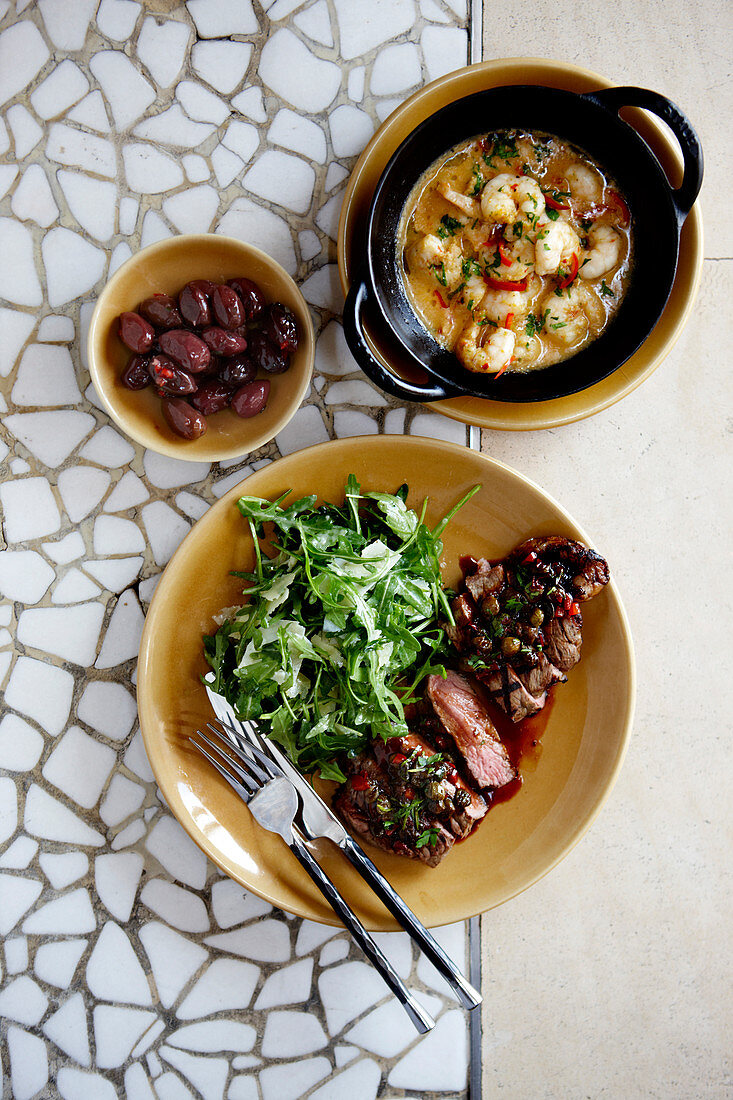 Beef with arugula, dumplings and shrimps on a mosaic table