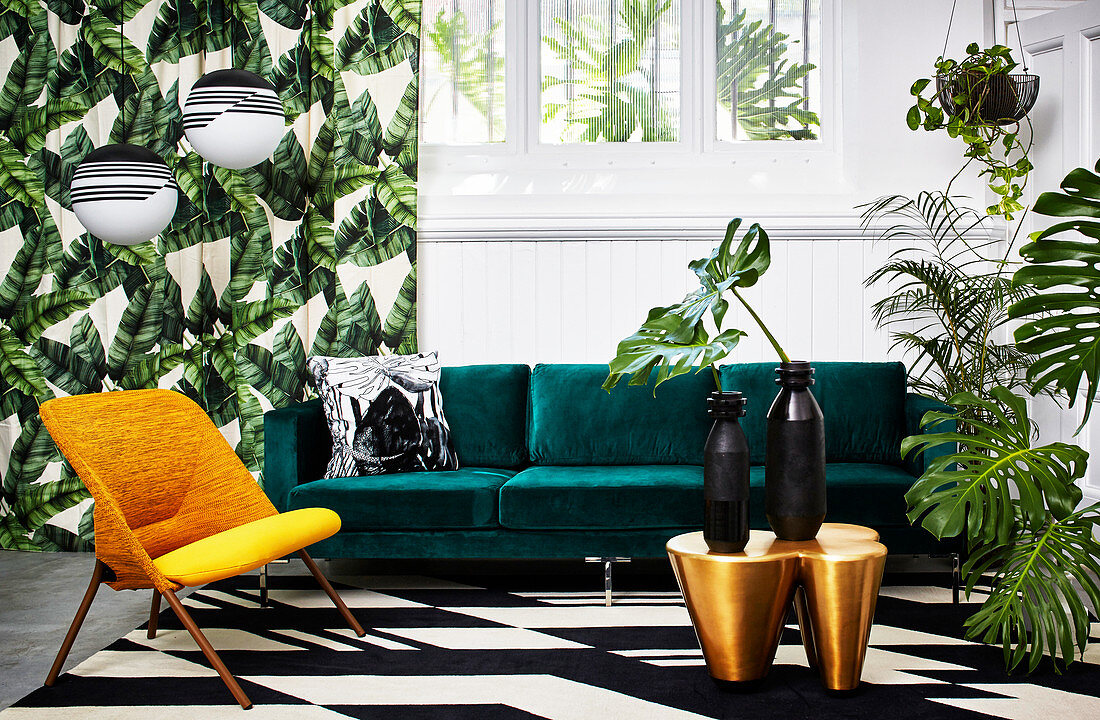 Green velvet sofa and houseplants in exotic living room