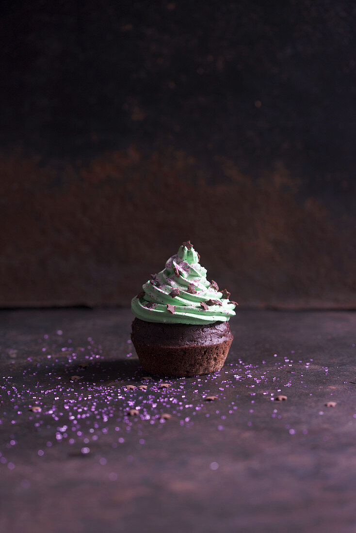 A chocolate cupcake with pistachio cream, sugar stars and edible glitter (vegan)