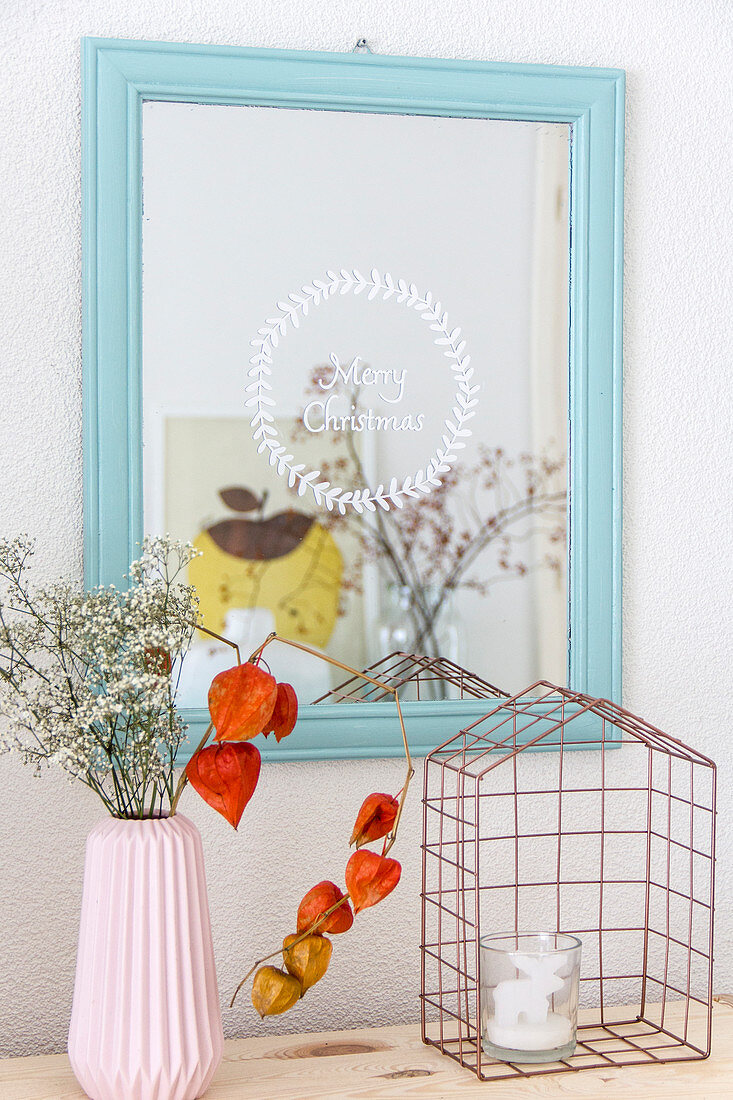 Metal cage below blue-framed mirror etched with Christmas greeting