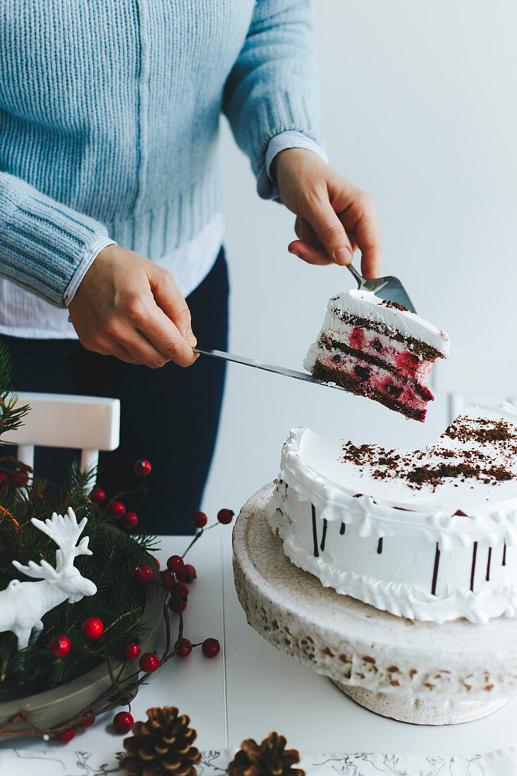 Junge Frau schneidet weihnachtliche Festtagstorte in Stücke